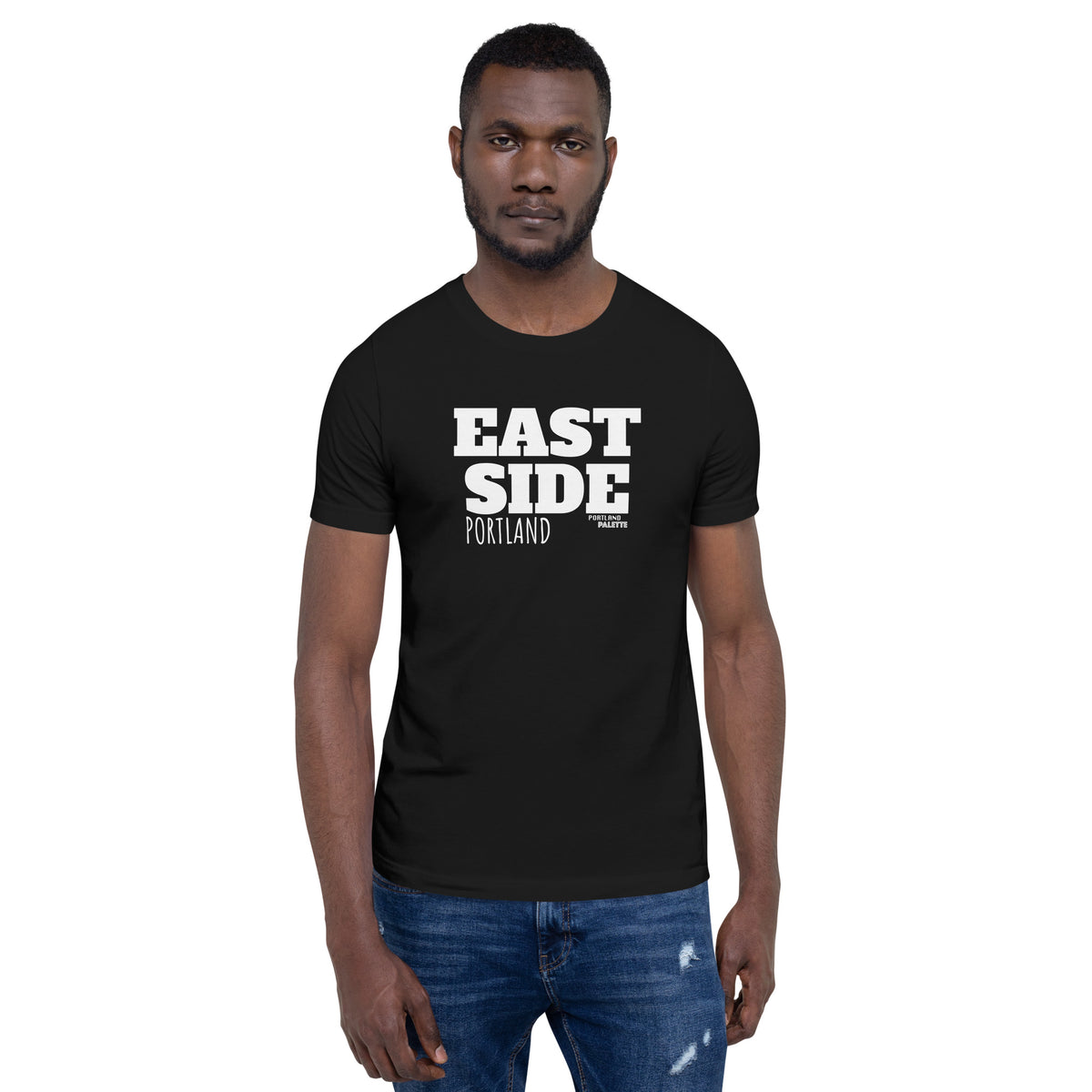 A man wearing a black short-sleeve t-shirt with 'EAST SIDE PORTLAND' printed in bold white text on the chest, paired with blue jeans, set against a plain white background.