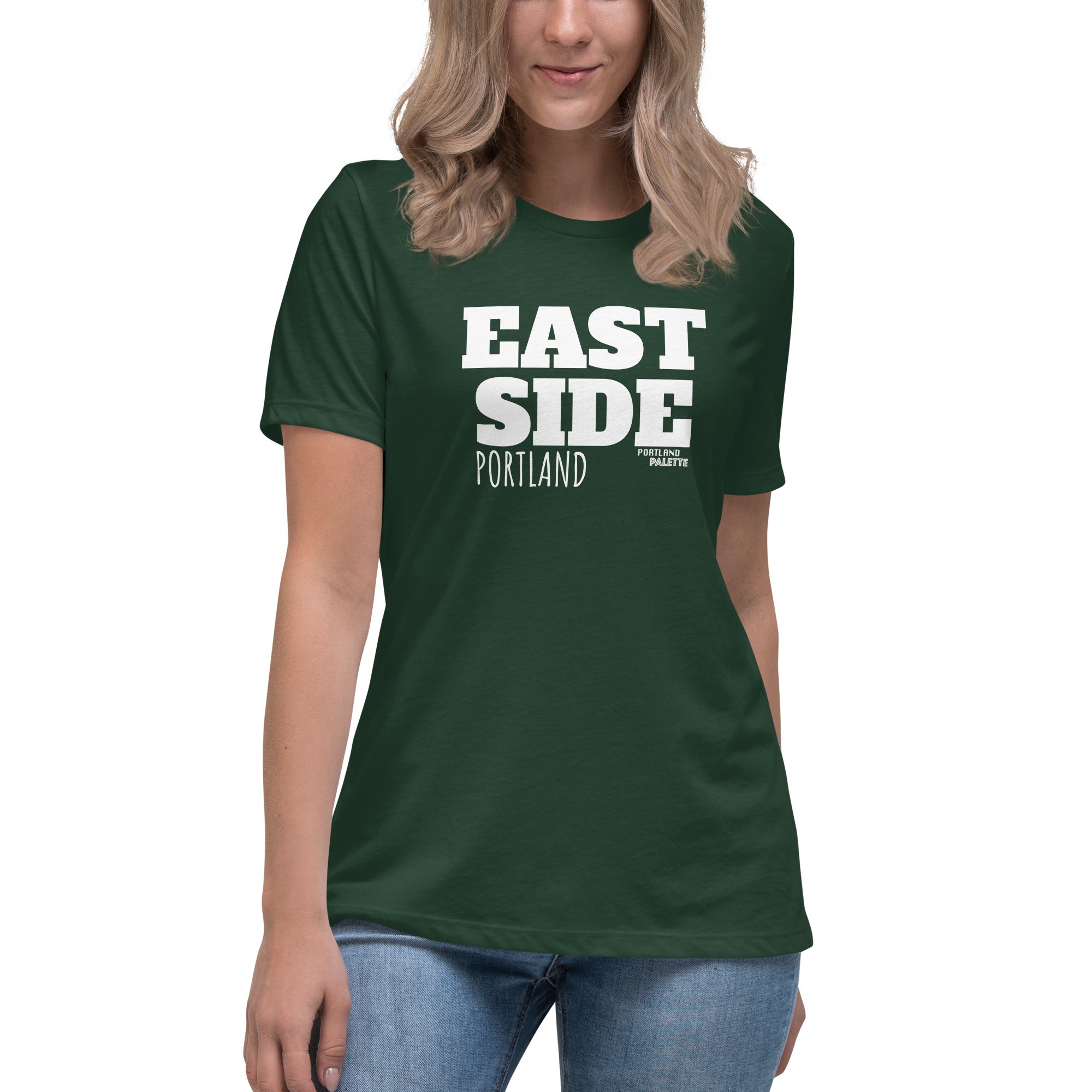 A woman wearing a dark green short-sleeve t-shirt with 'EAST SIDE PORTLAND' printed in bold white letters on the front, paired with blue jeans against a plain white background.